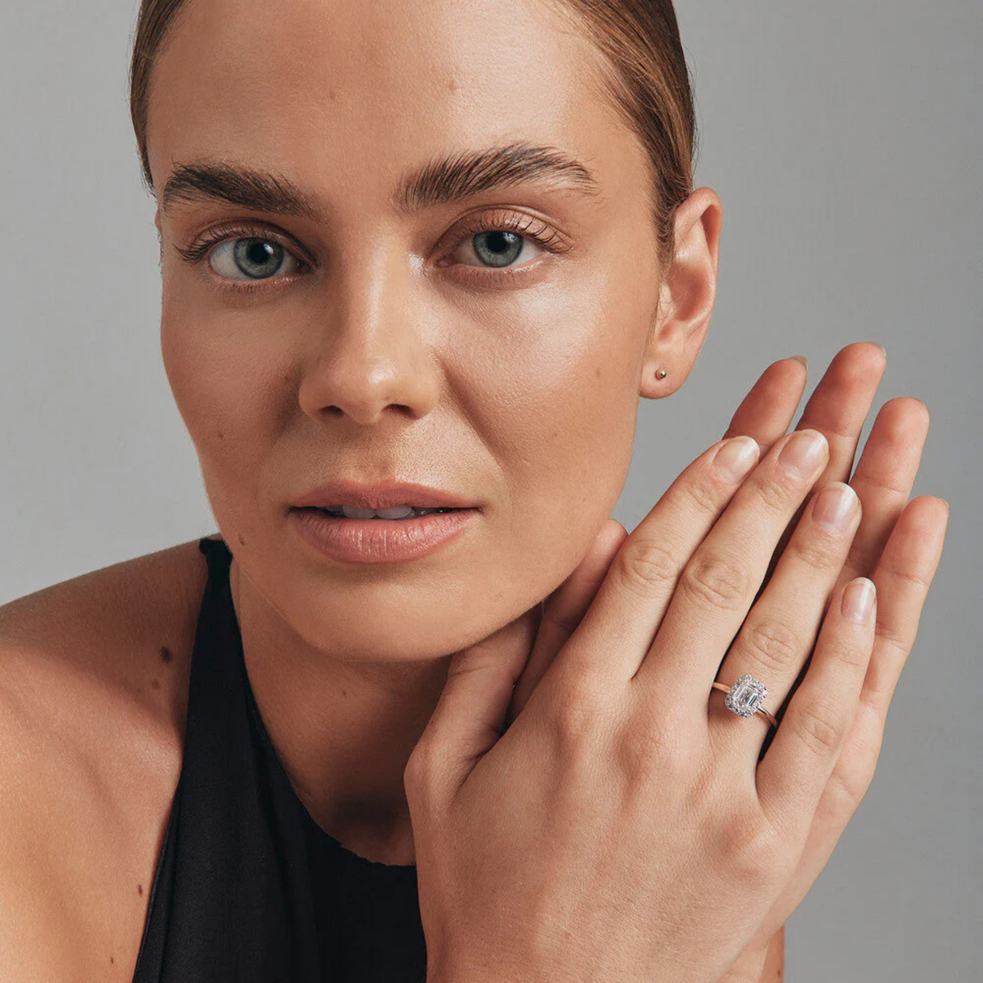 Close-up of a woman showcasing a 1.46 Carat TW Emerald cut laboratory-grown diamond halo engagement ring.