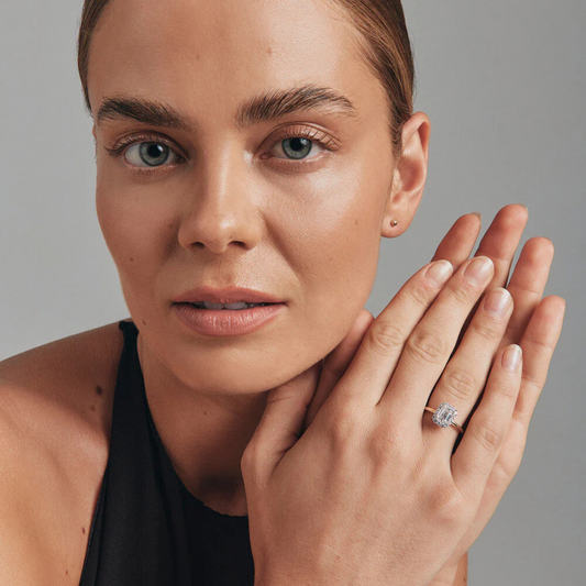 Close-up of a woman showcasing a 1.46 Carat TW Emerald cut laboratory-grown diamond halo engagement ring.